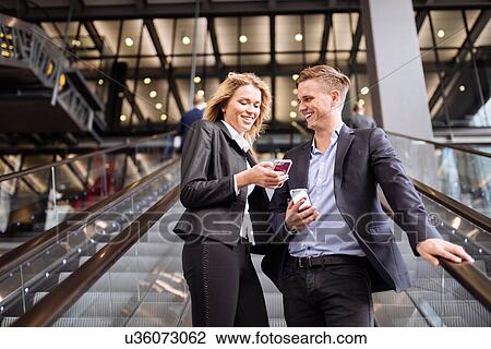 Businessman and businesswoman on escalator, London, UK View Large Photo Image Stock Image - Businessman and businesswoman on escalator, London, UK. Fotosearch