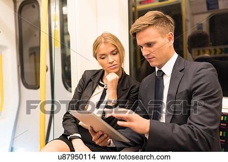 Businessman and businesswoman sharing digital tablet, London Underground, UK View Large Photo Image Picture - Businessman and businesswoman sharing digital tablet, London Underground, UK. Fotosearch