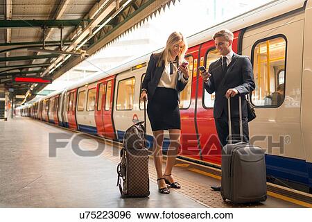 Businessman and businesswoman texting on platform, Underground station, London, UK View Large Photo Image Stock Photograph - Businessman and businesswoman texting on platform, Underground station, London, UK. Fotosearch