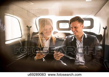 Businessman and businesswoman using smartphone in black cab, London, UK View Large Photo Image Stock Image - Businessman and businesswoman using smartphone in black cab, London, UK. Fotosearch