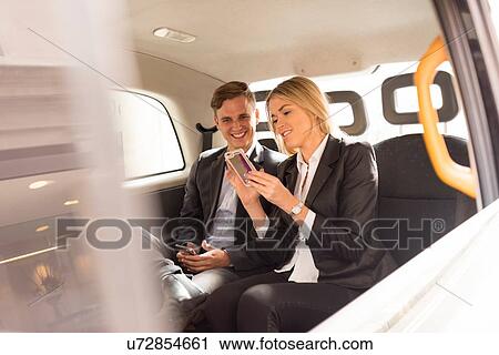 Businessman and businesswoman using smartphone in black cab, London, UK View Large Photo Image Stock Image - Businessman and businesswoman using smartphone in black cab, London, UK. Fotosearch