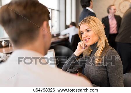 Stock Photograph - Businessman and businesswoman using laptop in cafe. Fotosearch