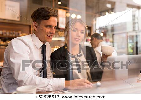 Businessman and businesswoman working on laptop in cafe View Large Photo Image Stock Image - Businessman and businesswoman working on laptop in cafe. Fotosearch
