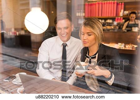 Stock Image - Businessman and businesswoman working on laptop in cafe. Fotosearch