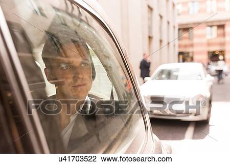 Stock Image - Businessman looking out of black cab, London, UK. Fotosearch