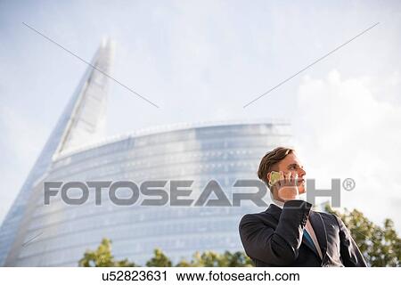 Stock Image - Businessman making call, buildings in background, London, UK. Fotosearch