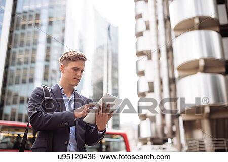 Businessman using digital tablet in street, London, UK View Large Photo Image Stock Photograph - Businessman using digital tablet in street, London, UK. Fotosearch
