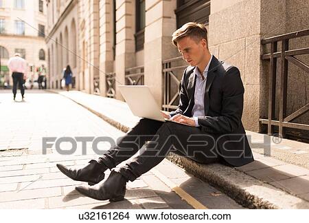 Businessman using laptop on kerb, London, UK View Large Photo Image Picture - Businessman using laptop on kerb, London, UK. Fotosearch