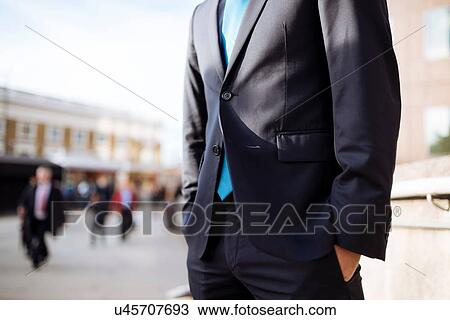 Stock Image - Businessman with hands in pocket, partially obscured, London, UK. Fotosearch