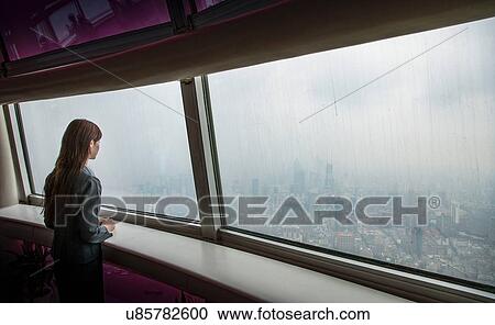 Businesswoman looking through skyscraper office window at Shanghai cityscape, China View Large Photo Image Stock Image - Businesswoman looking through skyscraper office window at Shanghai cityscape, China. Fotosearch