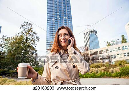 Stock Image - Businesswoman on smartphone, Warsaw, Poland. Fotosearch