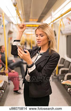 Picture - Businesswoman texting on tube, London Underground, UK. Fotosearch