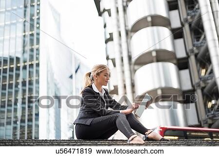 Stock Photo - Businesswoman using digital tablet in street, London, UK. Fotosearch