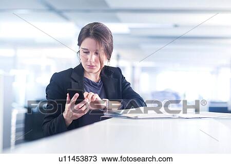 Businesswoman using smartphone in office View Large Photo Image Stock Image - Businesswoman using smartphone in office. Fotosearch