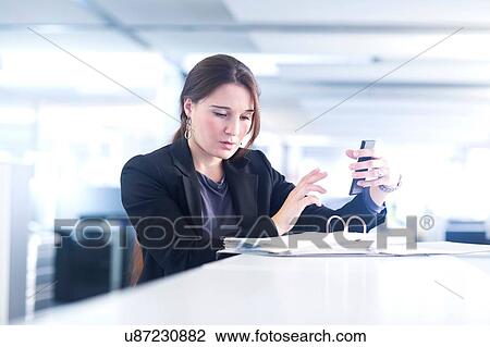 Businesswoman using smartphone in office View Large Photo Image Stock Image - Businesswoman using smartphone in office. Fotosearch