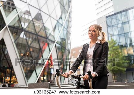 Stock Photo - Businesswoman with bike outside 30 St Mary Axe, London, UK. Fotosearch