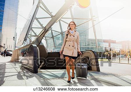 Businesswoman with wheeled suitcase by escalator View Large Photo Image Stock Photo - Businesswoman with wheeled suitcase by escalator. Fotosearch