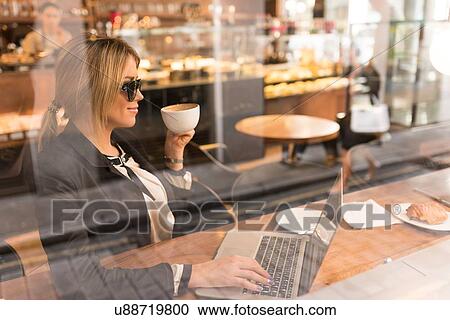 Stock Image - Businesswoman working on laptop in cafe. Fotosearch