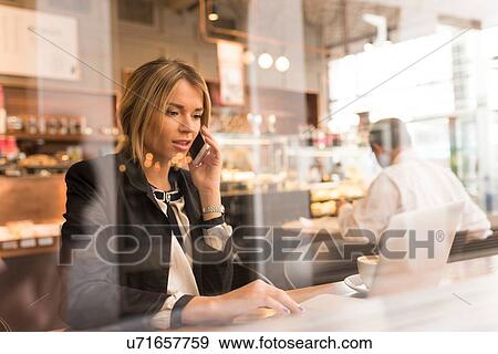 Stock Photo - Businesswoman working on laptop in cafe. Fotosearch