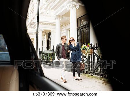 Stock Photo - Car window view of young couple strolling on street, London, England, UK. Fotosearch