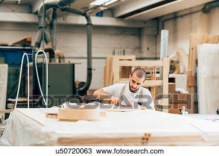 Stock Image - Carpenter at work in workshop. Fotosearch