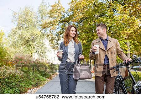 Casual businessman and woman pushing bike with coffee View Large Photo Image Stock Image - Casual businessman and woman pushing bike with coffee. Fotosearch