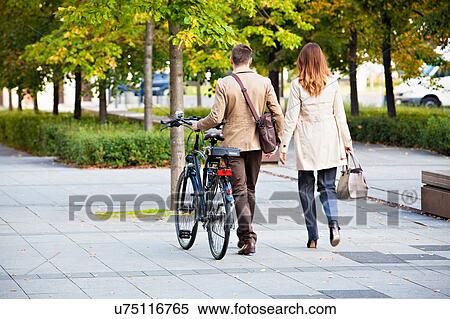 Stock Photography - Casual businessman and woman pushing bike. Fotosearch