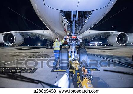 Stock Photo - Chief engineer inspecting A380 aircraft on runway at airport at night. Fotosearch