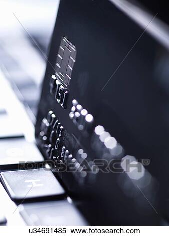 Stock Photography - Close up of black credit card standing on computer keyboard. Fotosearch