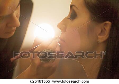 Stock Photography - Close up of young woman applying friends lip liner. Fotosearch