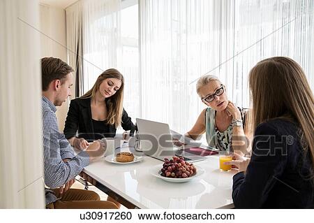 Colleagues sitting at table having business breakfast meeting View Large Photo Image Stock Image - Colleagues sitting at table having business breakfast meeting. Fotosearch