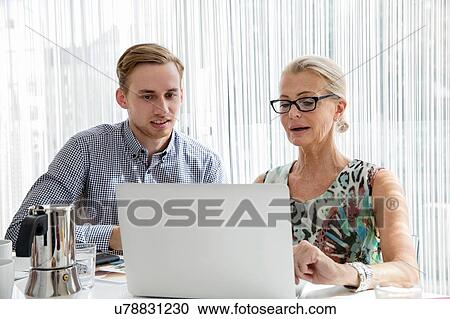 Colleagues sitting looking at laptop computer View Large Photo Image Stock Image - Colleagues sitting looking at laptop computer. Fotosearch
