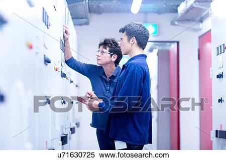 Stock Photography - Colleges in control room looking at switchgear. Fotosearch
