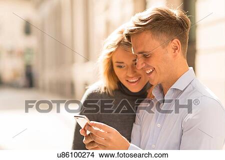 Couple sharing text message in street View Large Photo Image Picture - Couple sharing text message in street. Fotosearch