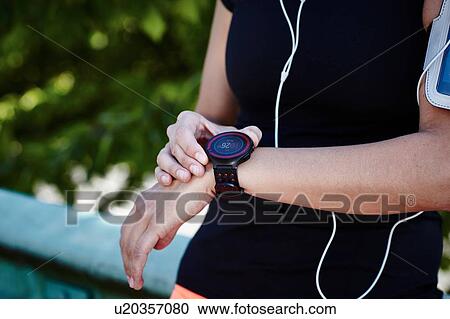 Stock Image - Cropped shot of young female runner setting smartwatch. Fotosearch