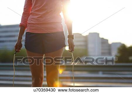 Stock Image - Cropped shot of young woman training with skipping rope on rooftop. Fotosearch