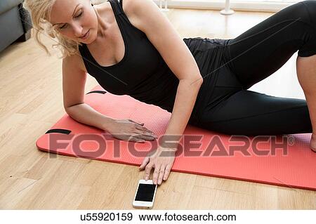 Cropped view of mature woman lying on side on yoga mat looking down using smartphone View Large Photo Image Stock Photo - Cropped view of mature woman lying on side on yoga mat looking down using smartphone. Fotosearch