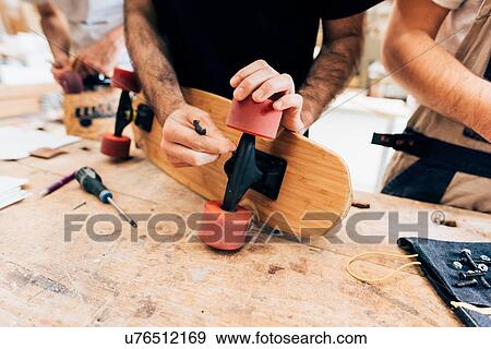 Cropped view of young men in workshop attaching wheels to skateboard View Large Photo Image Stock Photo - Cropped view of young men in workshop attaching wheels to skateboard. Fotosearch
