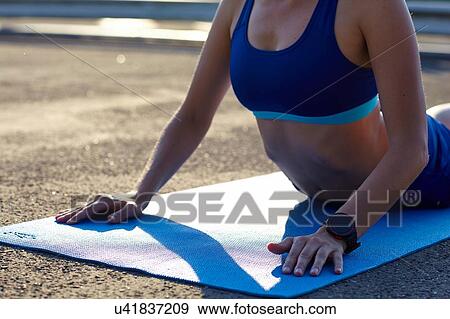 Stock Photo - Cropped view of young woman practicing yoga in urban parking lot. Fotosearch