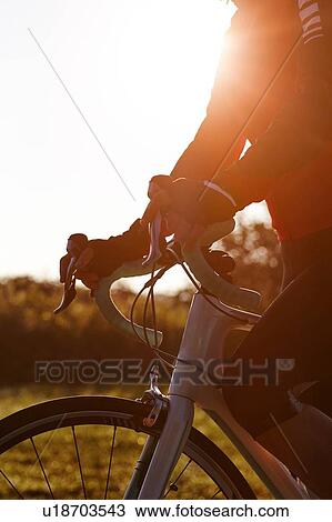 Stock Image - Cyclist riding during sunset. Fotosearch