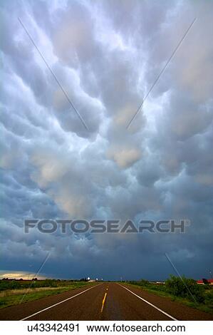 Stock Image - Diminishing perspective of open road and mammatus clouds after storms, near Tucumcari, New Mexico, USA. Fotosearch