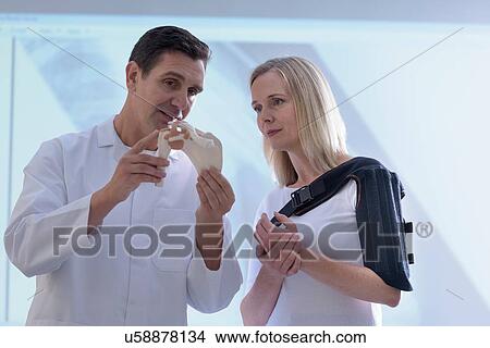 Picture - Doctor fitting orthopaedic sling to patient. Fotosearch