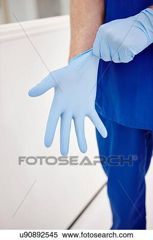 Stock Photography - Doctor putting on gloves. Fotosearch