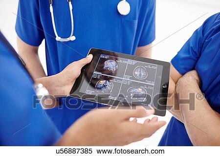 Stock Photography - Doctors looking at scans on digital tablet. Fotosearch