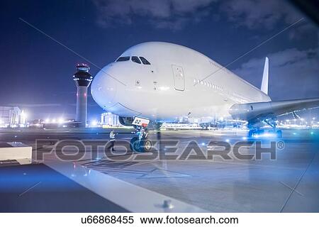 Stock Photography - Engineer communicating with pilot of A380 aircraft on runway at night. Fotosearch