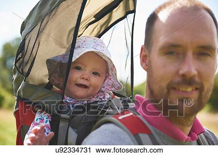Stock Image - Father carrying baby daughter on back. Fotosearch