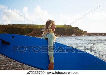 Female surfer walking toward sea, carrying surfboard View Large Photo Image Stock Photo - Female surfer walking toward sea, carrying surfboard. Fotosearch