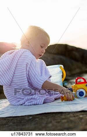 Female toddler sitting on beach playing with toy bucket View Large Photo Image Stock Image - Female toddler sitting on beach playing with toy bucket. Fotosearch