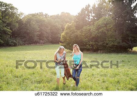 Front view of women carrying picnic blanket and flowers walking on field landscape smiling View Large Photo Image Stock Image - Front view of women carrying picnic blanket and flowers walking on field landscape smiling. Fotosearch