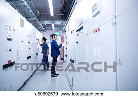 Full length side view of colleges in control room back to back looking at switchgear View Large Photo Image Stock Photo - Full length side view of colleges in control room back to back looking at switchgear. Fotosearch